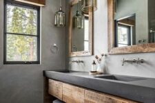 16 a catchy bathroom with concrete walls and a vanity, wooden storage units, pendant lamps and mirrors in rough wooden frames