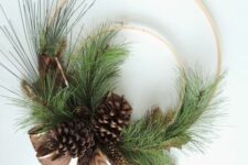 16 a simple rustic Christmas wreath of two embroidery hoops, evergreens, pinecones and a printed ribbon bow is cool