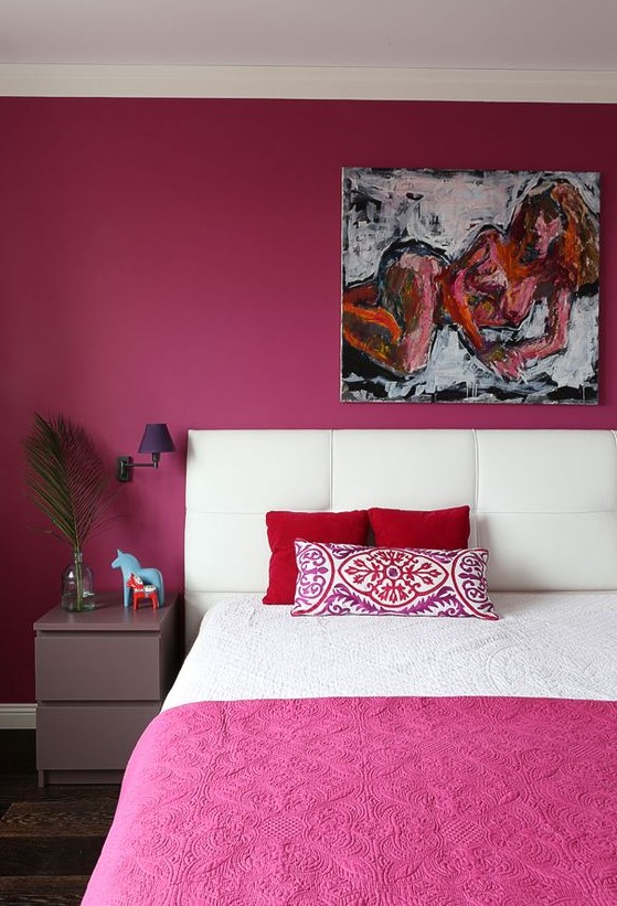 a quirky bedroom with a magenta statement wall and bedspread, a statement artwork, a lavender nightstand and purple sconces