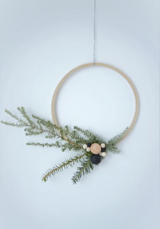 a simple Scandinavian Christmas wreath of an embroidery hoop, evergreens and wooden beads is a lovely decoration to rock