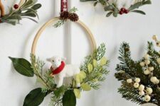 21 an arrangement of small embroidery hoops with evergreens, red berries and leaves plus sheep hanging on red ribbons