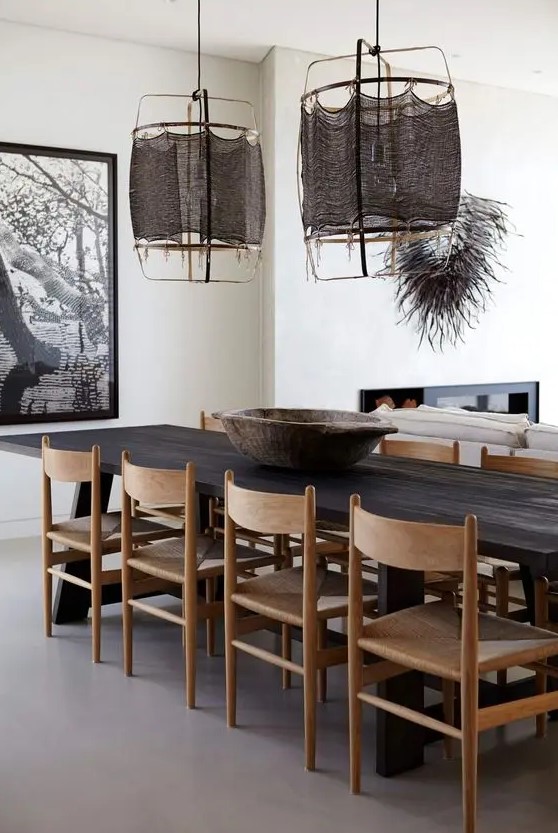 A bold and catchy dining space with a dark stained dining table, light stained chairs, dark pendant lamps and a bold artwork