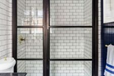 22 black and white graphic tiles on the floor, white subway tiles with black grout on the walls in a walk-in shower