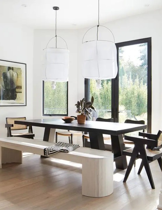 A bold dining zone with a view, a black dining table and chairs, a whitewashed bench and a light stained floor