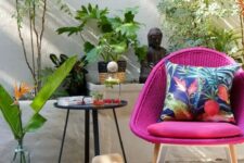 24 a cool outdoor nook with a woven magenta chair, a side table, a cushion, potted plants and beautiful Asian-inspired decor