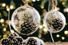 24 clear glass Christmas ornaments with snowy pinecones and white blooms inside will be a nice solution for boho or rustic holiday decor