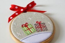28 a bright Christmas ornament of an embroidery hoop and some gift applique, with a red bow on top is a cool decoration to DIY