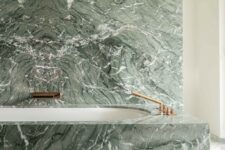 28 a green marble wall and a covered bathtub with brass fixtures create a really refined and luxurious space