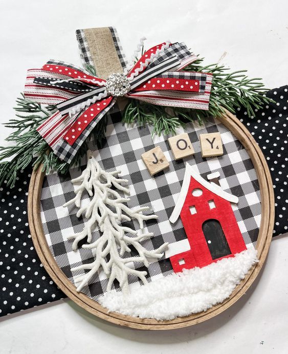 a cool embroidery hoop Christmas ornament with buffalo check, a red house and letters, a Christmas tree and a bow on top