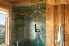 29 a gorgeous chalet bathroom done with light-stained wood and green marble in the shower, a tub with a view
