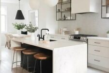 31 a chic contemporary kitchen with elegant white cabinets, a white tile backsplash, a black kitchen island with a white stone countertop and pendant lamps