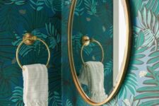 32 a beautiful bathroom with blue botanical wallpaper, a mirror in a gold frame, gold candleholders, a towel holder and lamps