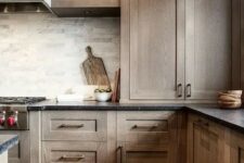 32 a dark-stained kitchen with shaker style cabinets, black stone countertops, a grey marble tile backsplash and open shelves