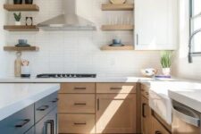 33 a modern farmhouse kitchen with light-stained cabinets, a navy kitchen island, white stone countertops and a skinny tile backsplash, black handles