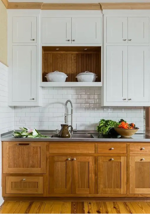 a modern farmouse kitchen with lower stained cabinets, upper white ones, a white subway tile backsplash, a metal countertop for a cozy look and maximal functionality