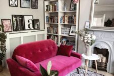 35 a neutral living room with a non-working fireplace, a large mirror, a bookcase, a magenta sofa and some potted plants