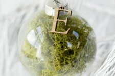37 a moss-filled clear glass Christmas ornament with a wooden monogram on top is a cool woodland decoration for your tree