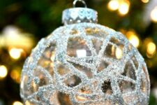 38 a clear glass Christmas ornament decorated with silver patterns is a shiny and cool decor idea for a Christmas tree