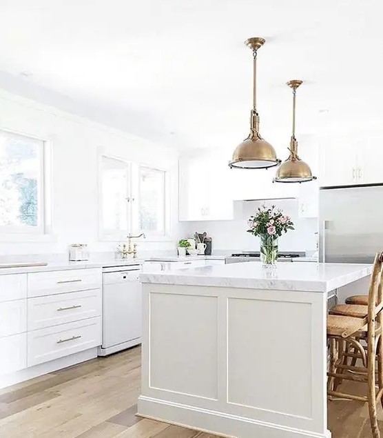 a white farmhouse kitchen with brass vintage touches and marble countertops for an eye-catchy touch