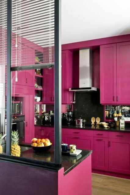 A stylish magenta kitchen with shaker cabinets, black countertops and a mirror backsplash, built in appliances and a glazed wall