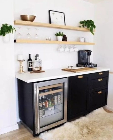 a small and catchy home bar with light-stained open shelves, black cabinetry, a wine cooler, various plants, bottles and candles