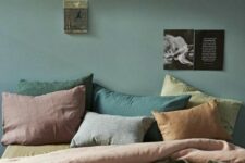 45 a muted-colored bedroom with a dark green wall, pillows of muted shades like rust, greens and mauve