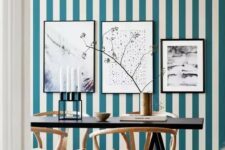 47 a chic dining room with a blue and white striped wall, a gallery wall, a black table and refined wooden chairs