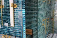 50 a catchy bathroom clad with blue tiles, finished off with gold fixtures and sconces looks wow