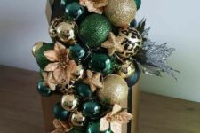 a Christmas gift box with lots of emerald and gold ornaments, faux blooms and stars plus silver branches