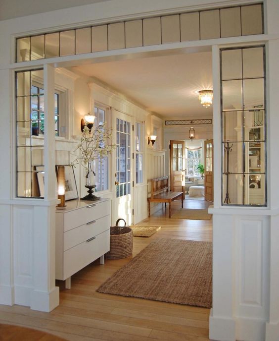 A beautiful vintage inspired white entryway with elegant furniture, a transom window and some sidelights