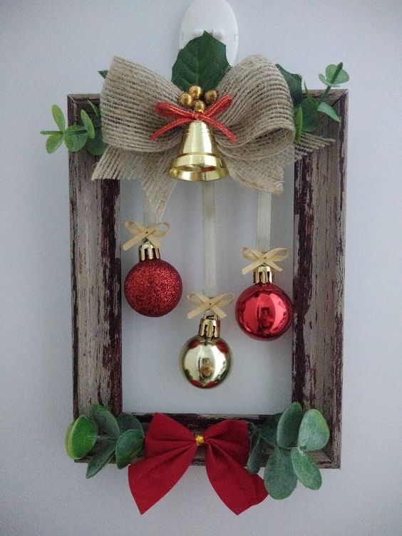 a cute frame Christmas wreath with red and gold ornaments, a gold bell on top, eucalyptus, leaves and a red bow is lovely