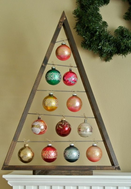A dark stained Christmas tree with colorful ornaments hanging is a stylish solution to decorate your Christmas mantel
