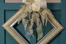 a decorative gold frame Christmas wreath with gilded leaves and a large ribbon bow on top is a fantastic idea for a glam space