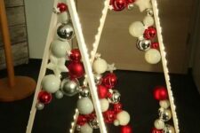 a duo of lit up frame Christmas trees with white, silver and red ornaments and some stars inside is amazing