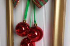 a gold frame Christmas wreath with red ornaments, green ribbon and a green and red plaid bow is a stylish idea