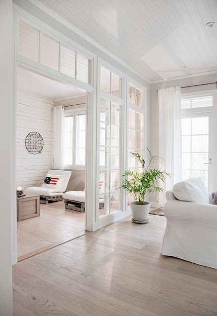 A light filled white space with glazed walls, transom windows, vintage white furniture is a lovely and welcoming space