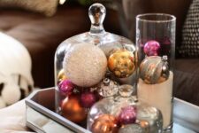 a mirror tray with cloches and a glass with vintage ornaments is a very elegant and chic Christmas decoration