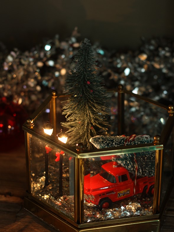 a stylish Christmas terrarium with gold glitter, a red truck with a Christmas tree and some street lamps plus one more tree
