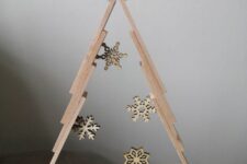 a tabletop frame Christmas tree decorated with some wooden snowflakes inside is a stylish idea for rustic decor