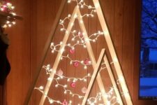an arrangement of plywood Christmas trees with lights and red and white ornaments is a super stylish modern solution