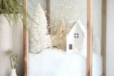 an oversized wooden candleholder with faux snow, mini houses and churches, a mini bottle brush tree and lights