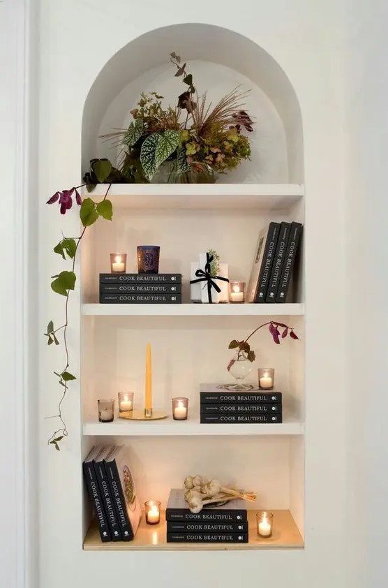 a lovely arched niche with shelves displaying books, candles and a potted plant is a stylish idea for a any space