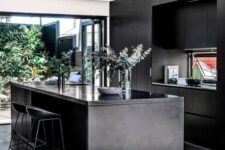 10 a contemporary moody kitchen with sleek black cabinetry, a kitchen island, a glazed wall with an entrance to a courtyard