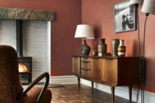 10 a rich-colored living room with burgundy walls, a hearth, a vintage credenza, a floor and table lamp
