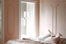 16 a refined vintage-inspired bedorom with blush molding walls, blush and white bedding, a wooden floor and a paper lamp