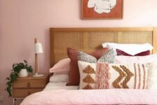 17 a stylish modern bedroom with light pink walls, pink, neutral and burgundy bedding, wooden furniture and a statement artwork