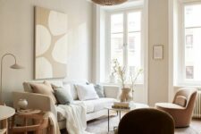 19 a warm-colored neutral living room with greige walls, a creamy sofa with neutral pillows, a tan chair and a side table