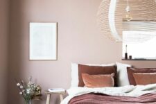 21 a beautiful attic bedroom with blush walls, a bed with contrasting bedding, a dark-stained wooden bench and a woven pendant lamp