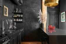 21 a moody yet bold kitchen with black cabinetry, black walls, a wooden ceiling, a gold chandelier and pampas grass in a vase