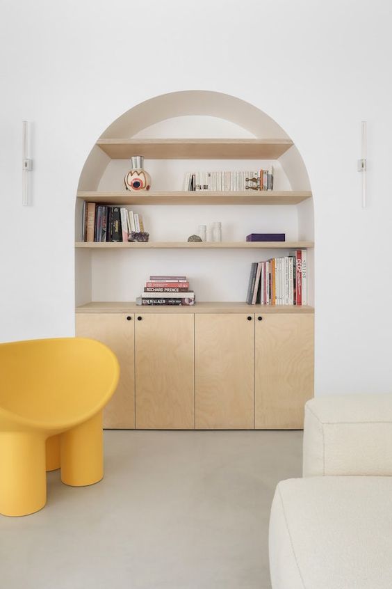 an arched niche with light-stained shelves with books and decor and a built-in cabinet for storage is a lovely idea